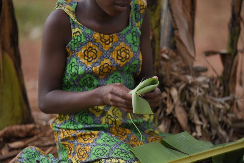 Young girl folding leaves to use as menstrual pads.